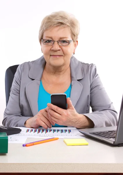 Idosa mulher de negócios usando telefone celular e trabalhando em sua mesa no escritório, conceito de negócio — Fotografia de Stock