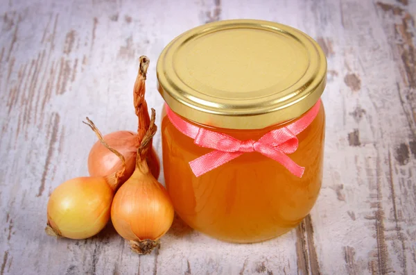 Miel orgánica fresca en frasco de vidrio y cebollas sobre fondo de madera, nutrición saludable y fortalecimiento de la inmunidad — Foto de Stock