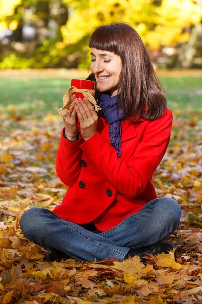Lachende vrouw in herfst park met warme drank thee of koffie — Stockfoto