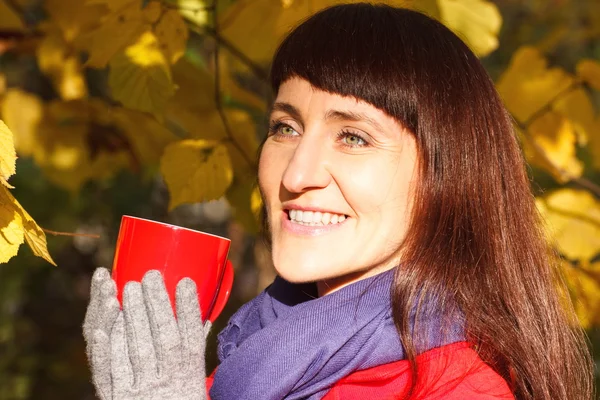Lachende vrouw in herfst park met warme drank thee of koffie — Stockfoto