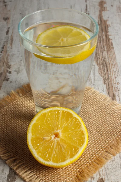 Свежий лимон и стакан чистой воды с ломтиком лимона, холодным лимонадом — стоковое фото