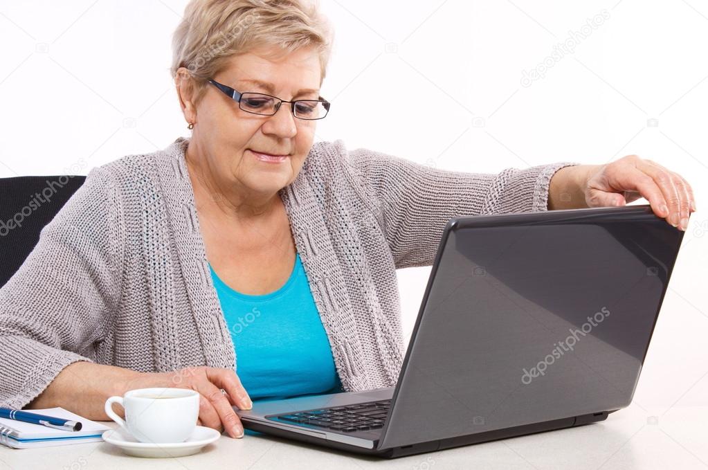 Elderly senior woman closing laptop on table at home