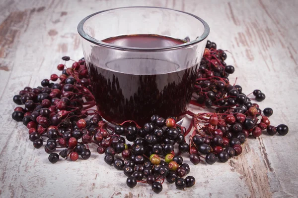 Bunch of fresh elderberry with juice on old wooden background, healthy nutrition — Stock Photo, Image