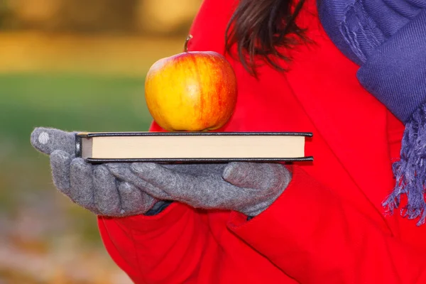 Ruka ženy držící knihu a apple na podzim park — Stock fotografie