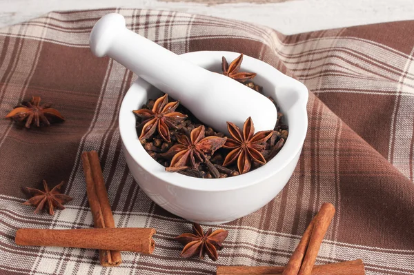 Fragrant cloves and anise in mortar and spices on rustic board