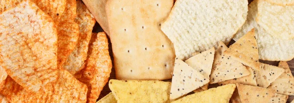 Montón de galletas crujientes y patatas fritas saladas, concepto de comida poco saludable — Foto de Stock