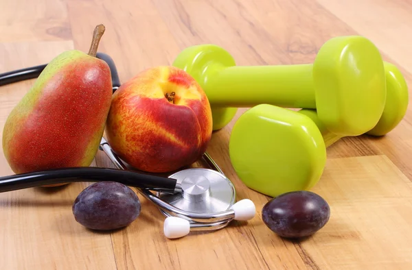 Estetoscópio médico, frutas e halteres para uso na aptidão — Fotografia de Stock