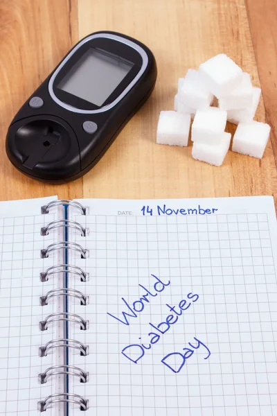 Glucometer, dia mundial da diabetes escrito em caderno e cubos de açúcar — Fotografia de Stock