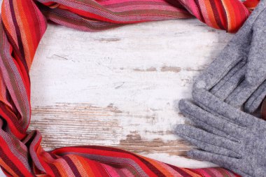 Woolen gloves and colorful shawl with copy space for text, old rustic wooden background