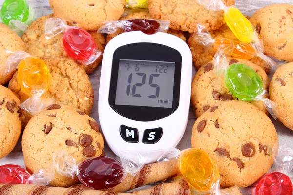 Glucometer y caramelos coloridos con galletas, diabetes, reducción de comer dulces — Foto de Stock