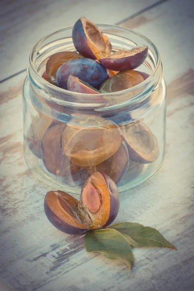 Vintage photo, Heap of plums in glass jar on wooden table in garden — Stock fotografie