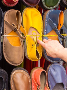 Hand of woman with colorful leather shoes on stall at the bazaar