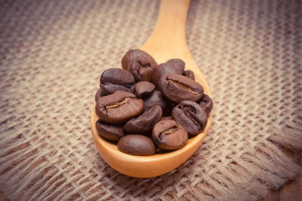 Vintage foto, Heap de grãos de café com colher de madeira sobre tela de juta — Fotografia de Stock