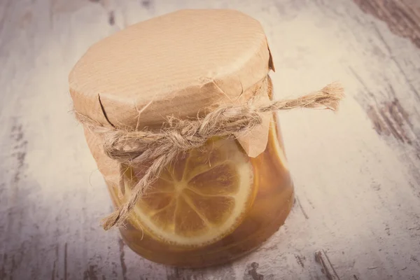 Foto vintage, Limón con miel en tarro de vidrio sobre mesa de madera, nutrición saludable — Foto de Stock