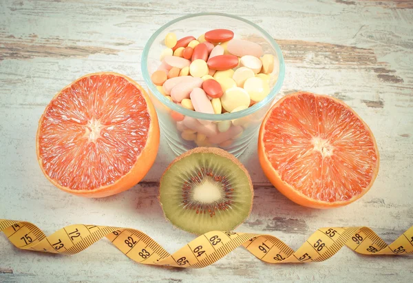 Vintage Fotoğraf, doğal meyve, santimetre ve hapları, zayıflama, sağlıklı beslenme ve sağlık takviyeleri arasında seçim — Stok fotoğraf