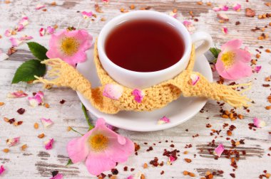 Çay ile eski rustik ahşap arka plan üzerinde yabani gül çiçek