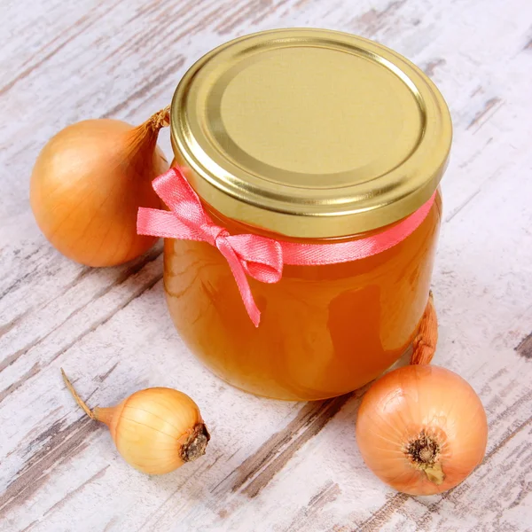 Miel orgánica fresca en frasco de vidrio y cebollas sobre fondo de madera, nutrición saludable y fortalecimiento de la inmunidad — Foto de Stock