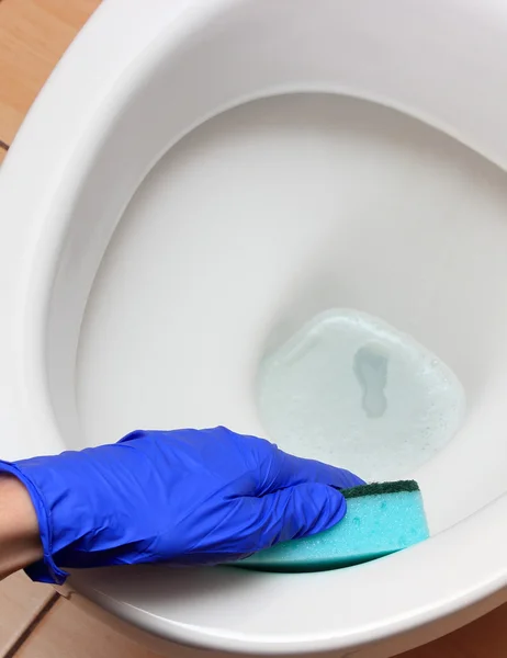 Main de femme en gant bleu nettoyage cuvette de toilette — Photo