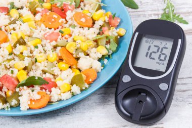 Glikoz ölçer, şeker seviyesi, kuskus ve sebzeli taze salata. Şeker hastaları için hafif vejetaryen yemeği