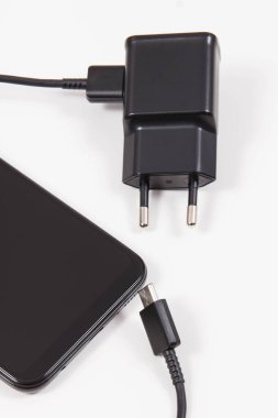 Cep telefonu ve şarjlı şarj aleti. Akıllı telefon şarj oluyor. Beyaz arkaplan