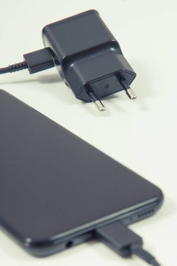 Şarj aletine bağlı akıllı telefon. Telefon şarj oluyor. Beyaz arkaplan
