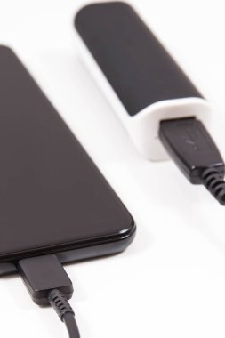 Dış siyah enerji bankası akıllı telefon veya cep telefonunu şarj ediyor. Beyaz arkaplan