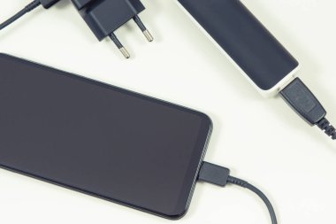 Güç bankasına bağlı akıllı telefon ve şarj aletinin fişi. Telefon şarj oluyor. Beyaz arkaplan