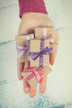 Klasik fotoğraf, Noel, Sevgililer Günü, doğum günü ya da kar arka planındaki diğer kutlamalar için paketlenmiş hediyeli bir kadın eli.
