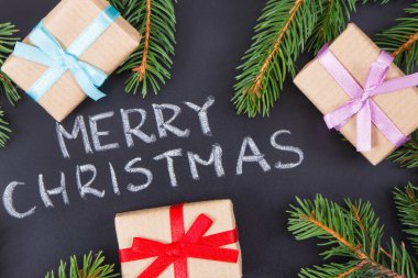 Yazı, Mutlu Noeller, kurdele ve yeşil ladin dallarıyla paketlenmiş hediyeler. Noel zamanı için dekorasyon