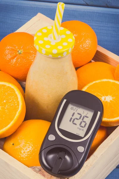 Glucose meter for checking sugar level and healthy coctail or juice from citrus fruits. Concept of diabetes, diet and slimming