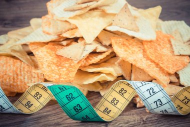 Klasik fotoğraf, çıtır çıtır patates cipsli bant ölçüsü ve köy tahtasındaki kurabiyeler, zayıflama konsepti, sağlıksız ve tuzlu gıda yeme kısıtlaması