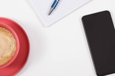 Akıllı telefon, not almak için sütlü kahve ve not defteri. İş ya da cep telefonuyla rahatlama. Beyaz arka plan. Metin için yer