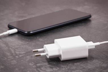 Şarj aletine bağlı siyah akıllı telefon. Telefon şarj ediliyor.