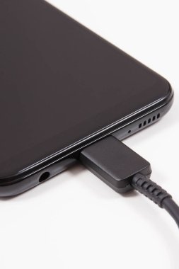 Şarj aletinin fişi cep telefonuna bağlı. Akıllı telefon şarj oluyor. Beyaz arkaplan