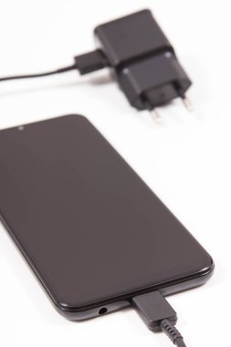 Şarj cihazına bağlı cep telefonu. Akıllı telefon şarj oluyor. Beyaz arkaplan