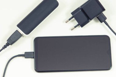 Güç bankasına bağlı akıllı telefon ve şarj aletinin fişi. Telefon şarj oluyor. Beyaz arkaplan