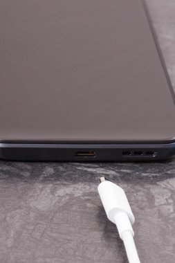 Siyah cep telefonu ve bağlanmamış şarj kablosu. Akıllı telefon şarj oluyor. Siyah arkaplan