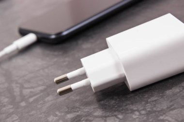 Şarj aletine bağlı siyah akıllı telefon. Telefon şarj ediliyor.