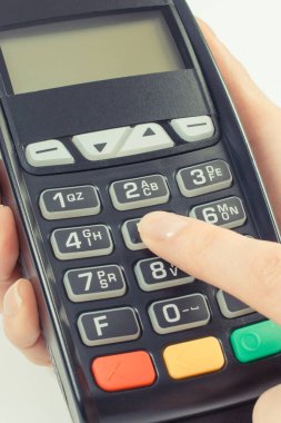 Ödeme terminalini kullanan bir kadın eli. Kişisel kimlik numarasını girin. Farklı şeyler için para ödemeden..