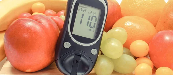 Glucose meter with sugar level and fresh ripe fruits. Healthy eating during diabetes concept