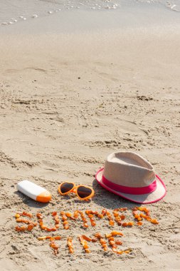 Yazı, kehribar taşlarından, güneş gözlüklerinden, güneş losyonundan ve hasır şapkadan yapılmış, güneş banyosu konsepti, yaz ve tatil zamanı, kumsalda kumdaki kum üzerindeki yazılar için metin alanı