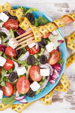 Centimetre ve taze Yunan salatası, beyaz peynir ve sebzeli. Sağlıklı yaşam tarzları, yiyecekler ve zayıflama kavramı