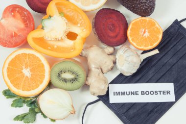 Yazılı bağışıklık güçlendirici, taze olgun sağlıklı meyve ve sebzeler içinde doğal vitaminler ve koruyucu maske var. Covid-19 zamanlarında bağışıklık güçlendirici