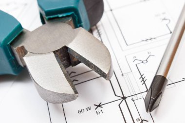 Metal pense ve tornavida elektrik inşaat diyagramlarının üzerinde duruyor. Ev konsepti inşa ediliyor