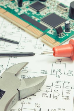 Üzerinde transistörler, rezistörler ve kapasitör olan bir devre kartı. Elektronik diyagram, multimetre kablo ve hassas aletler. Teknoloji