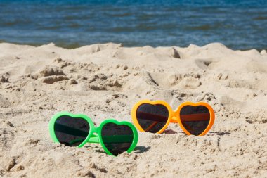 Kumsalda kumsalda güneşten korunmak için güneş gözlüğü. Seyahat ve tatil zamanı kavramı