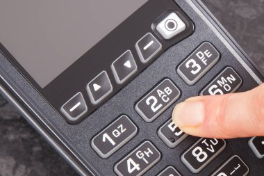 PIN kodunu ödeme terminaline giriş yapan bir kadın eli. Alışveriş için para ödemeden. Kredi kartı okuyucu. Finans kavramı