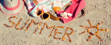 Yazın, kehribar taşı ve aksesuarlardan oluşan güneş şeklinde bir yazı. Rahatlamak için ya da kumsalda güneşlenmek için. Seyahat ve tatil zamanı kavramı