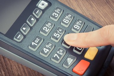 PIN kodunu ödeme terminaline giriş yapan bir kadın eli. Alışveriş için para ödemeden. Kredi kartı okuyucu. Finans kavramı