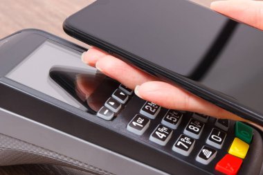 Kredi kartı okuyucu ve cep telefonunu nakit ödemelerde kullanıyor. Ödeme terminali. Finans ve bankacılık kavramı